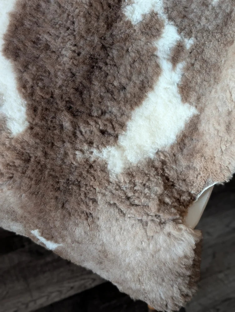 A plush tibet highland spotted sheepskin throw in soft brown and white with dense fluffy texture 41.5 x 26 inches