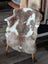 A plush brown and white tibet highland spotted sheepskin rug draped over a wooden chair for cozy decor