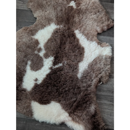 A plush 41.5 x 26 inch tibet highland spotted sheepskin rug with brown and white natural wool pattern grade a