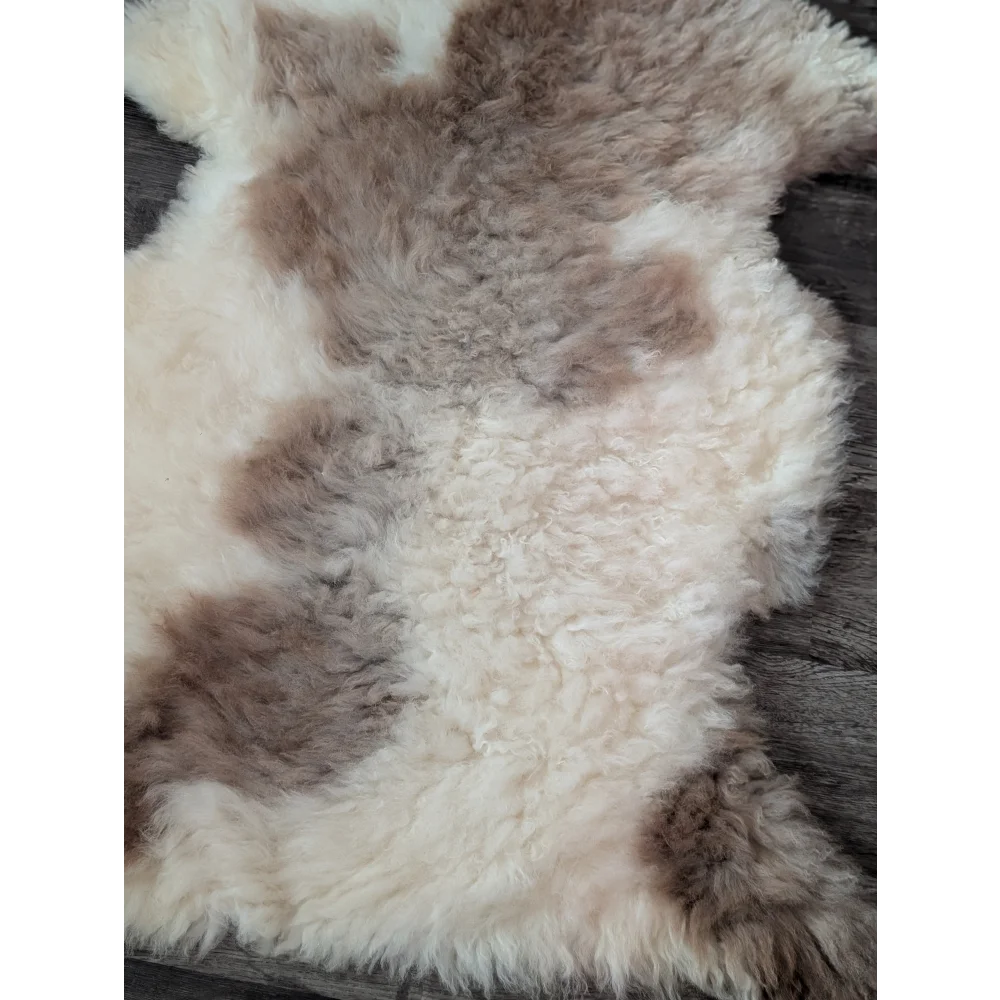 A soft fluffy tibet highland spotted sheepskin rug in cream and brown mottled pattern 40.5 x 26 inches