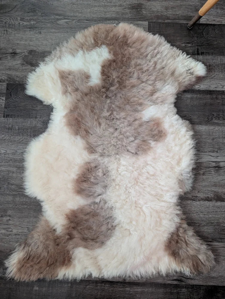 A soft fluffy tibet highland spotted sheepskin rug with creamy white and light brown patches for cozy decor