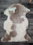 A soft fluffy tibet highland spotted sheepskin rug with creamy white and light brown patches for cozy decor