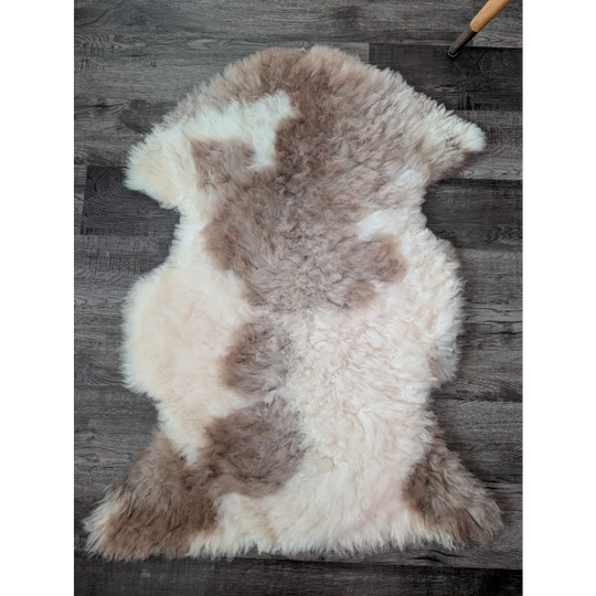A soft fluffy tibet highland spotted sheepskin rug with creamy white and light brown patches for cozy decor