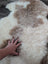 A soft fluffy tibet highland spotted sheepskin rug in creamy white and light brown patches grade a quality