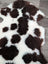 A plush tibet highland spotted grade a sheepskin rug in black and white spotted pattern measuring 39 by 25 inches