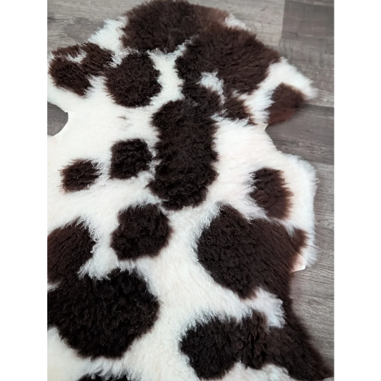 A plush tibet highland spotted grade a sheepskin rug in black and white spotted pattern measuring 39 by 25 inches