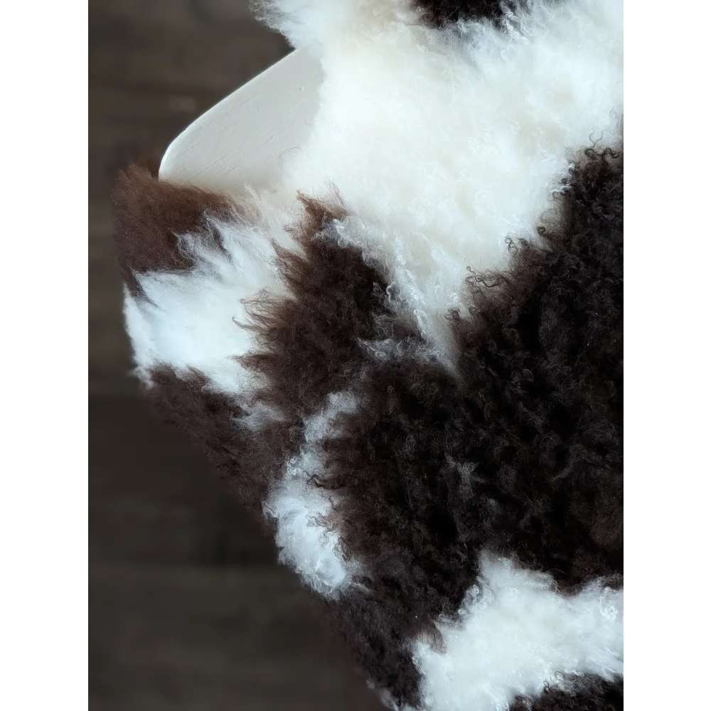A plush curly brown and white tibet highland spotted sheepskin blanket with soft fluffy texture 39 x 25 inches