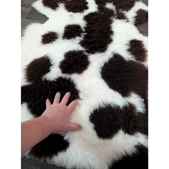 A plush 39 x 25 inch tibet highland spotted sheepskin rug with black and white cow print pattern