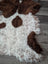 A plush 43 x 27 inch tibet highland spotted sheepskin rug with curly white and brown cow-print and natural edge