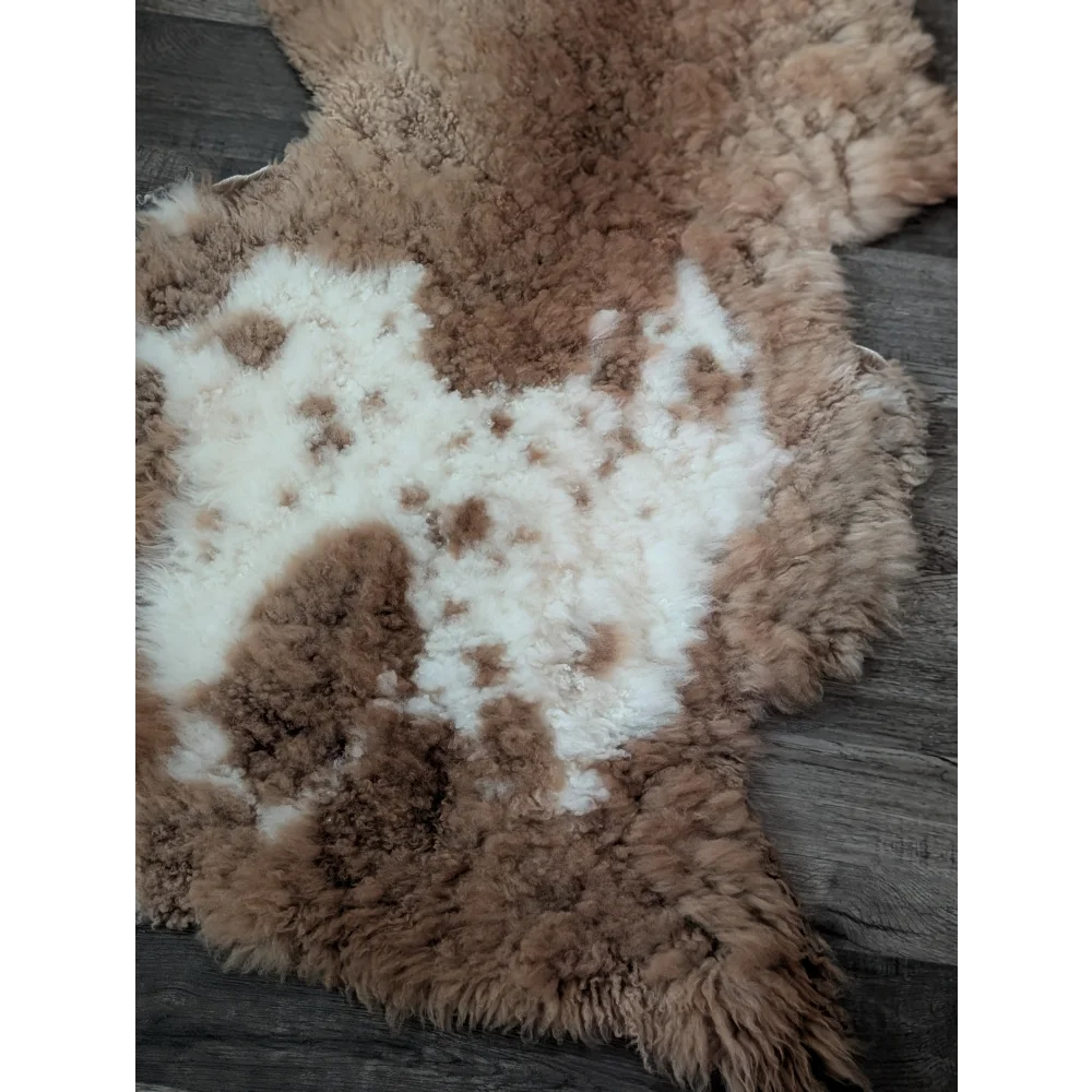 A plush tibet highland spotted sheepskin rug with natural brown and white mottled pattern 44 x 26 inches