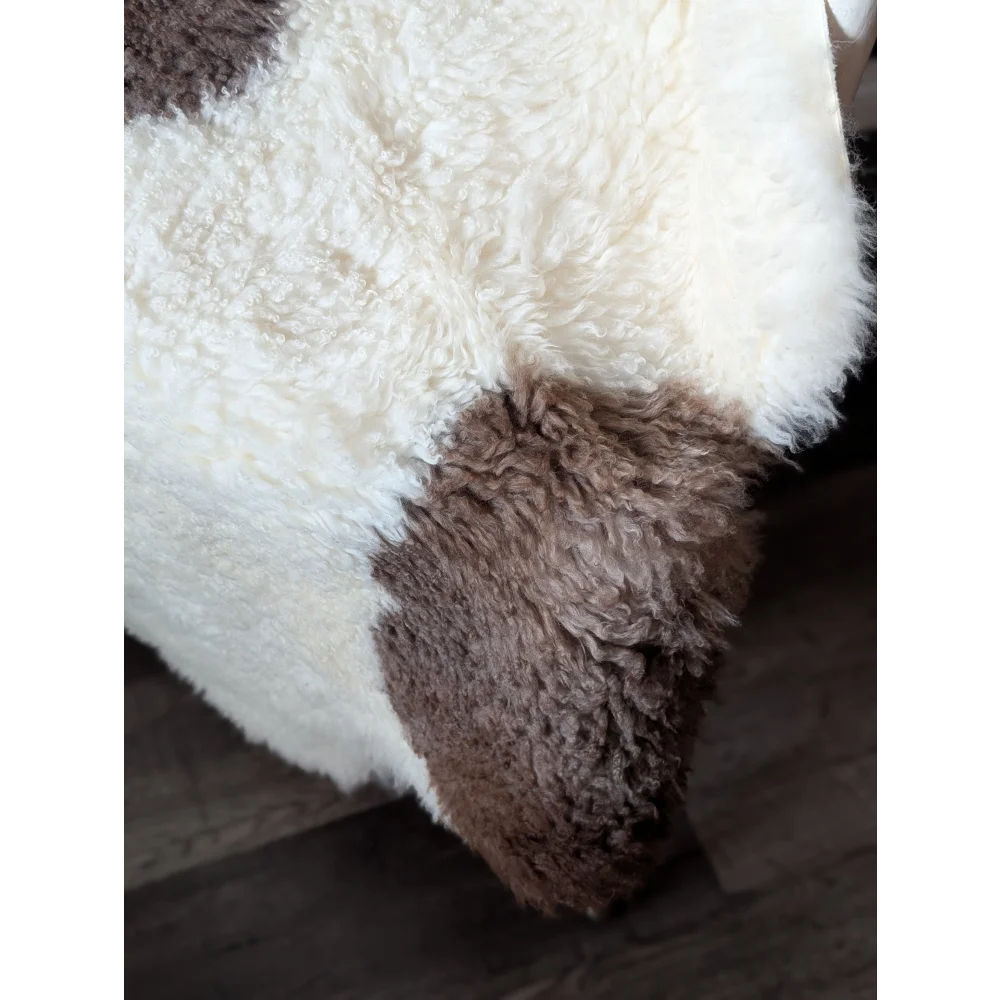 A plush cream and brown tibet highland spotted sheepskin rug with soft curly texture perfect for cozy decor