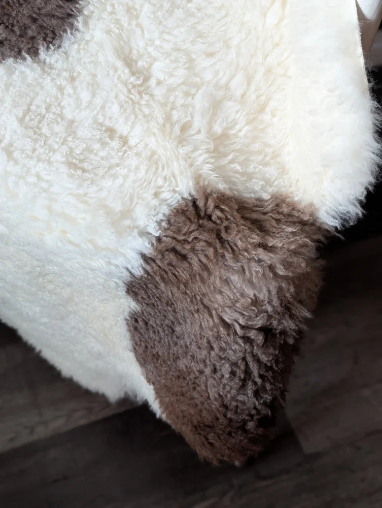 A plush cream and brown tibet highland spotted sheepskin rug with soft curly texture perfect for cozy decor