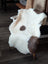 A plush white and brown highland spotted tibet highland spotted sheepskin rug draped over a wooden chair