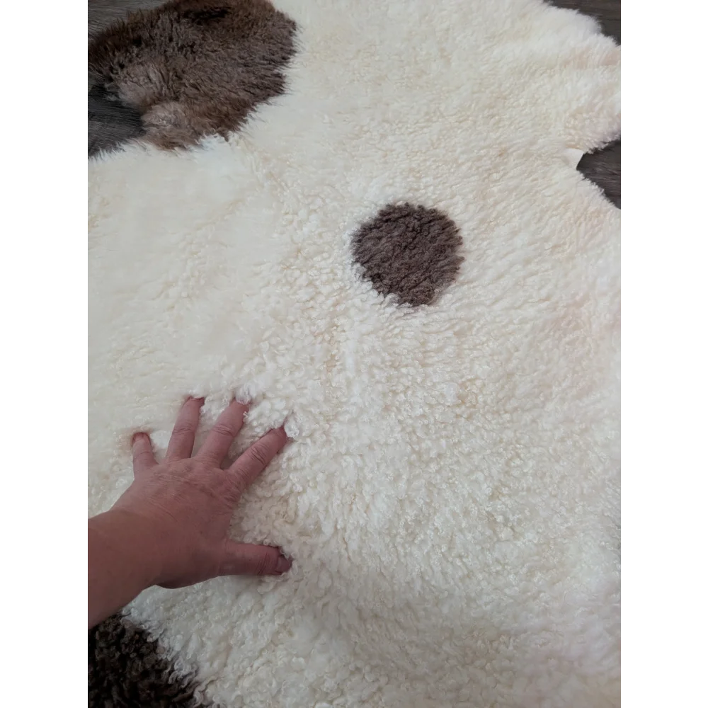 A plush white and brown tibet highland spotted sheepskin rug shaped like a dog perfect for cozy decor