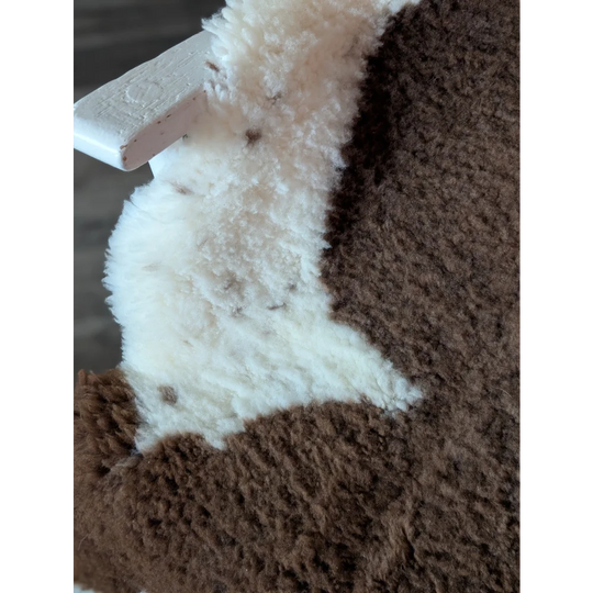 Brown and white fluffy stuffed animal on a 41 x 26 inch gorgeous tibet highland spotted sheepskin grade a rug