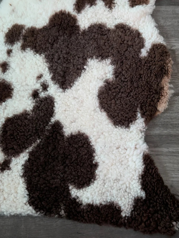 A plush tibet highland spotted faux shearling rug in brown and white cow print measuring 41 by 24 inches