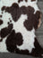 A plush tibet highland spotted faux shearling rug in brown and white cow print measuring 41 by 24 inches