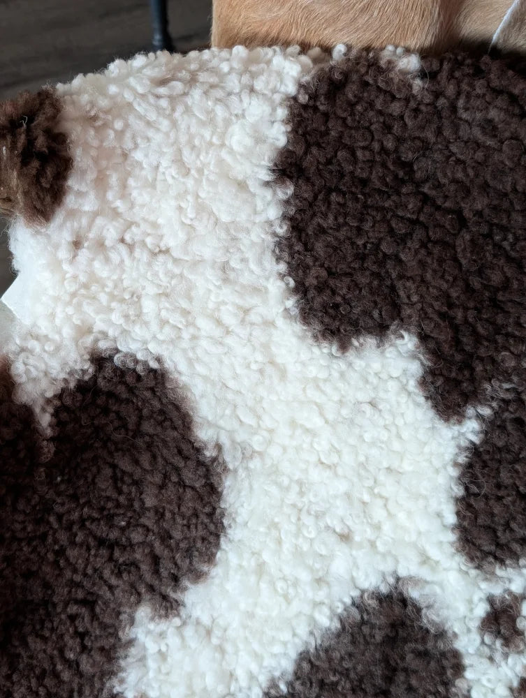 A cozy 41 x 24 inch tibet highland spotted sheepskin blanket in white and brown with soft curly texture