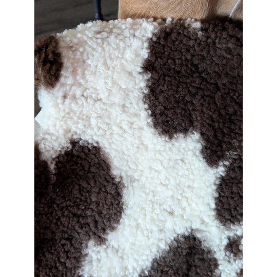 A cozy 41 x 24 inch tibet highland spotted sheepskin blanket in white and brown with soft curly texture