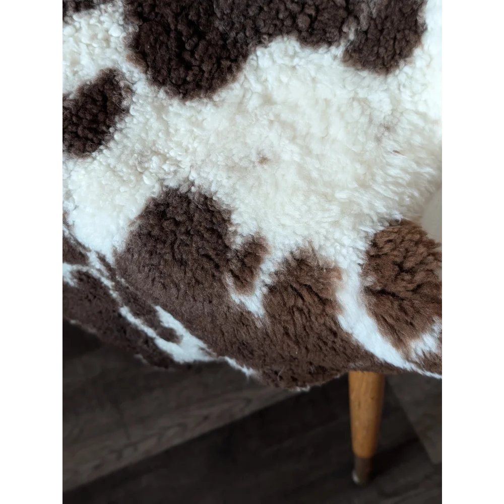 Cozy brown and white tibet highland spotted sheepskin faux fur blanket draped over wooden chair leg