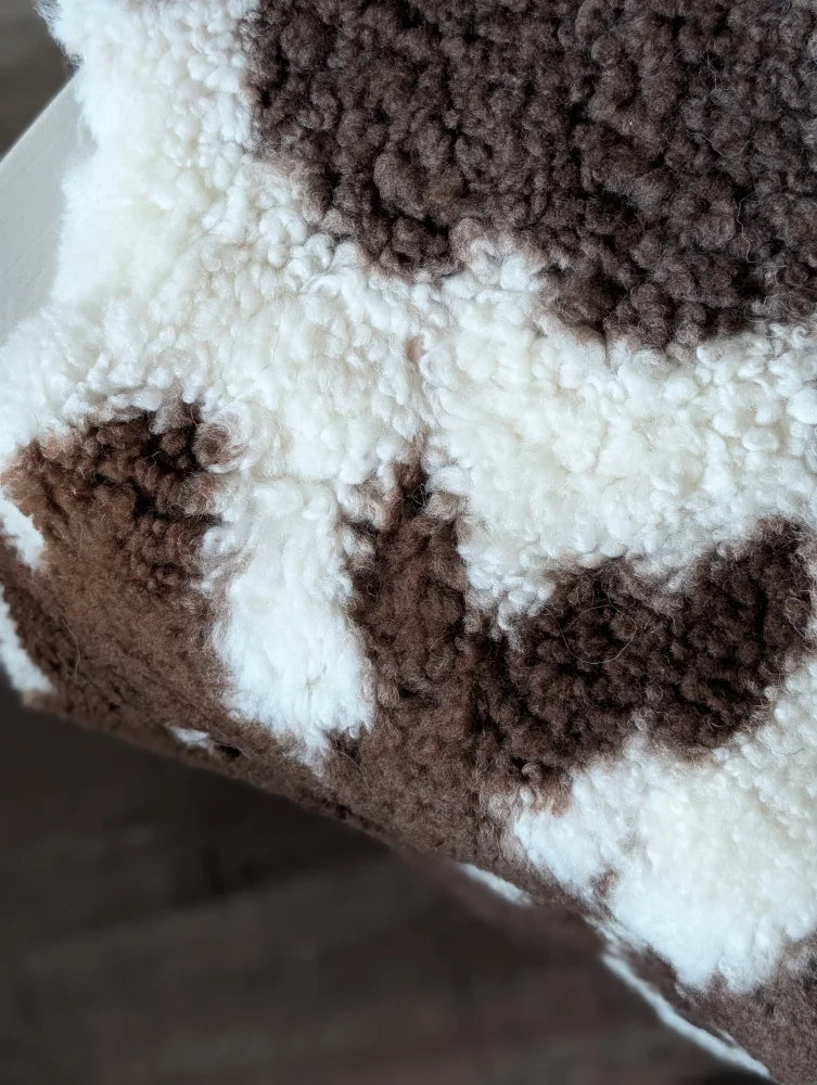 A cozy brown and white highland spotted sheepskin fleece blanket with soft plush texture for warmth and comfort