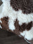 A cozy brown and white highland spotted sheepskin fleece blanket with soft plush texture for warmth and comfort