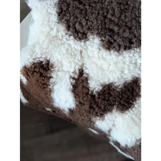 A cozy brown and white highland spotted sheepskin fleece blanket with soft plush texture for warmth and comfort