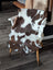 Brown and white tibet highland spotted sheepskin blanket draped over wooden chair measuring 41 by 24 inches