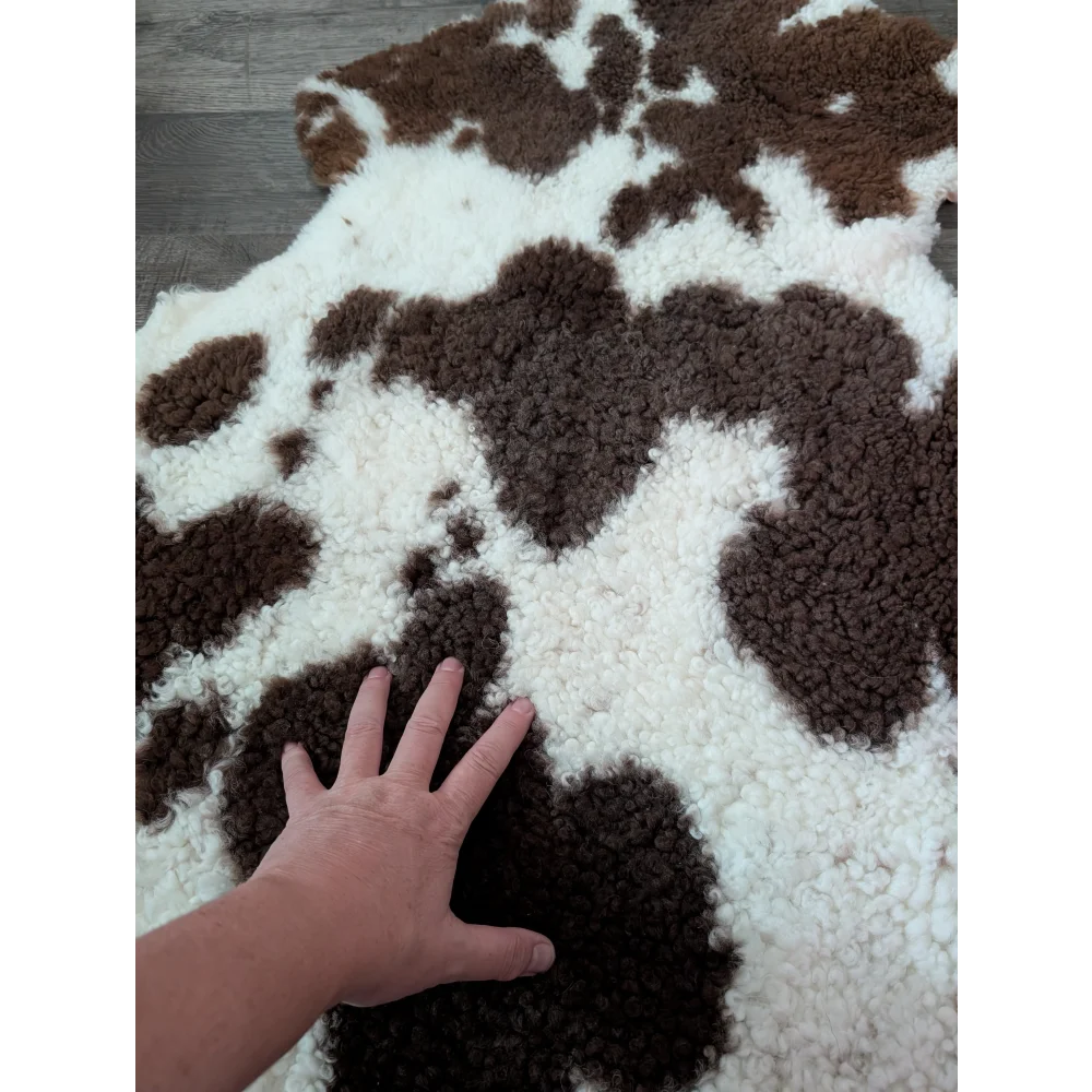 A plush brown and white tibet highland spotted sheepskin rug with a soft textured surface measuring 41 x 24 inches