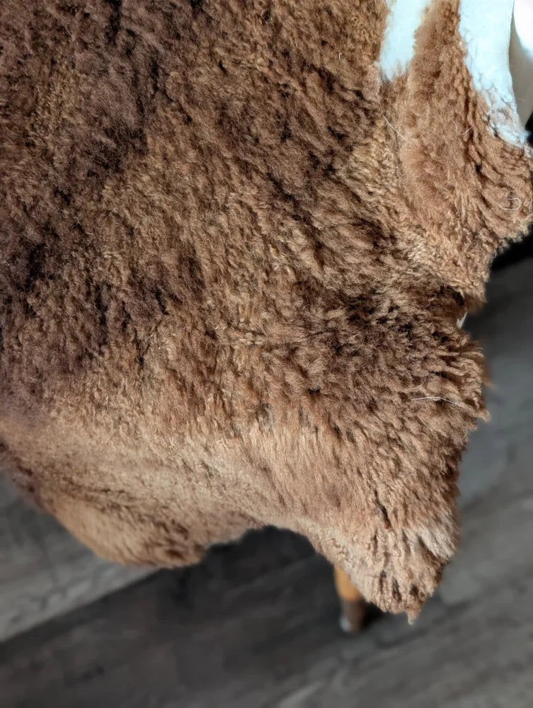 A thick brown tibet highland spotted sheepskin rug with soft curly texture and natural shade variations