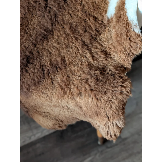 A thick brown tibet highland spotted sheepskin rug with soft curly texture and natural shade variations