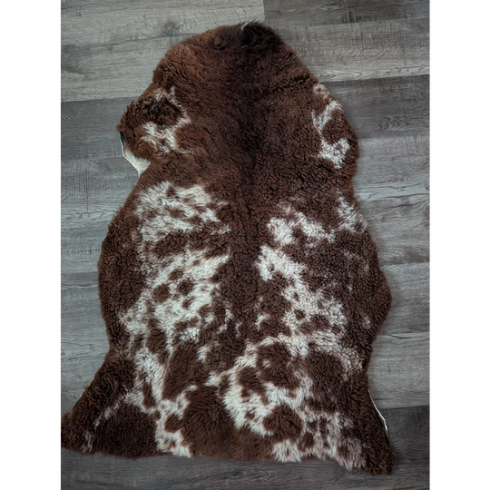 Brown and white speckled tibet highland spotted sheepskin rug with plush natural fur texture 41 x 25 inches