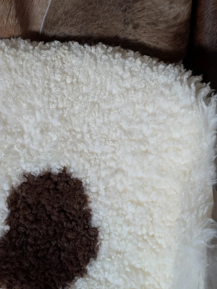 White fluffy pillow with a brown circular patch made from grade a tibet highland spotted sheepskin 44 x 26 inches