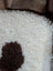 White fluffy pillow with a brown circular patch made from grade a tibet highland spotted sheepskin 44 x 26 inches