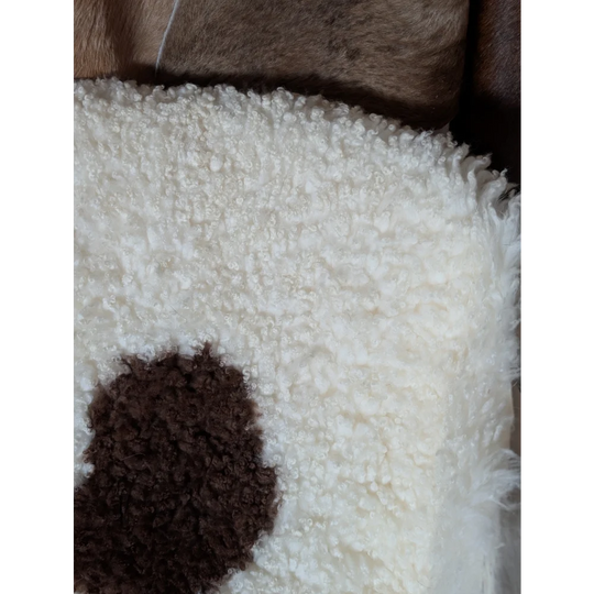 White fluffy pillow with a brown circular patch made from grade a tibet highland spotted sheepskin 44 x 26 inches