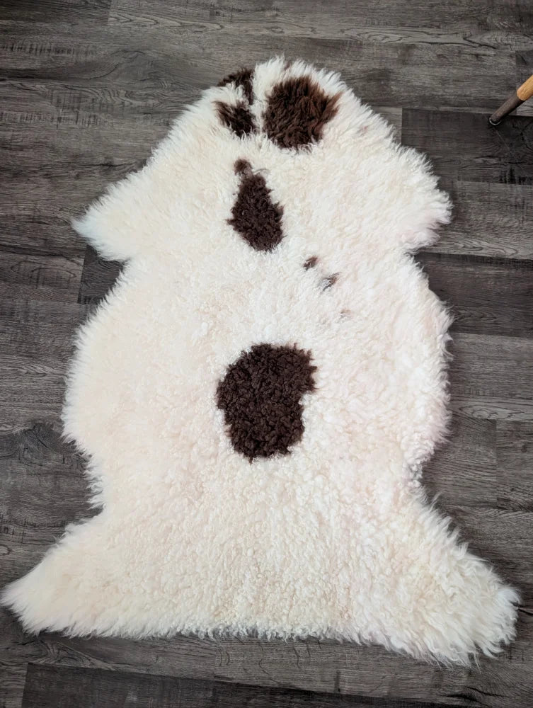 Fluffy white tibet highland spotted sheepskin rug with three dark brown patches in a vertical line 44 x 26 inches