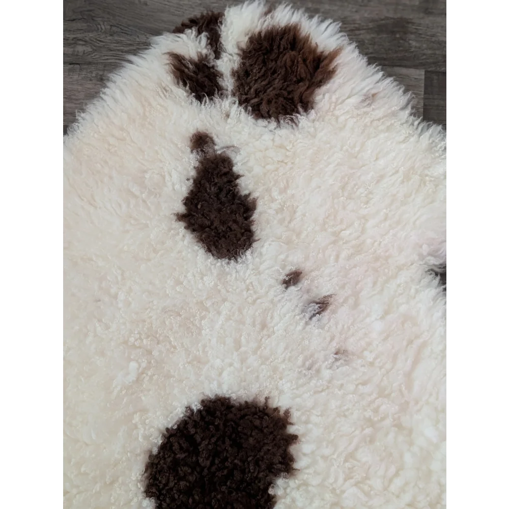 A plush white and brown paw print rug made from soft tibet highland spotted sheepskin grade a material