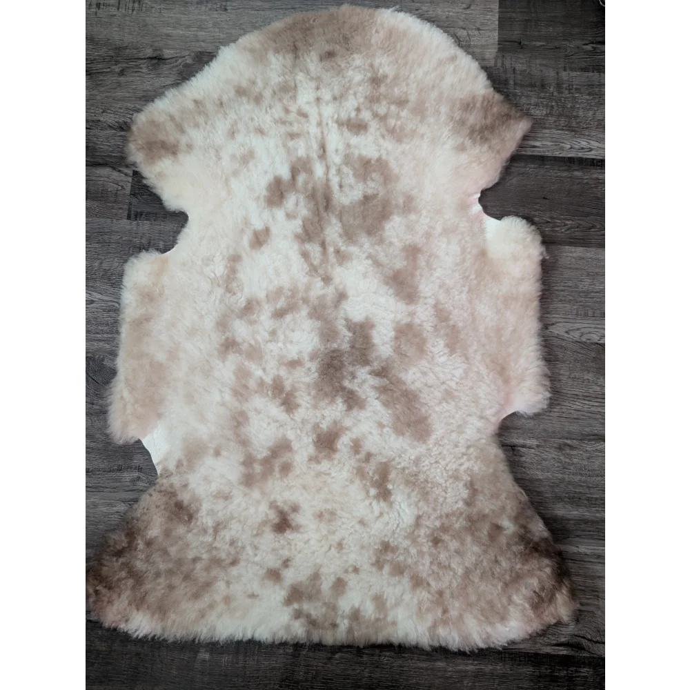 A soft fluffy tibet highland spotted sheepskin rug with natural cream and light brown mottled pattern ideal for decor
