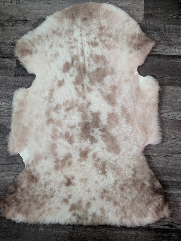 A soft fluffy tibet highland spotted sheepskin rug with natural cream and light brown mottled pattern ideal for decor
