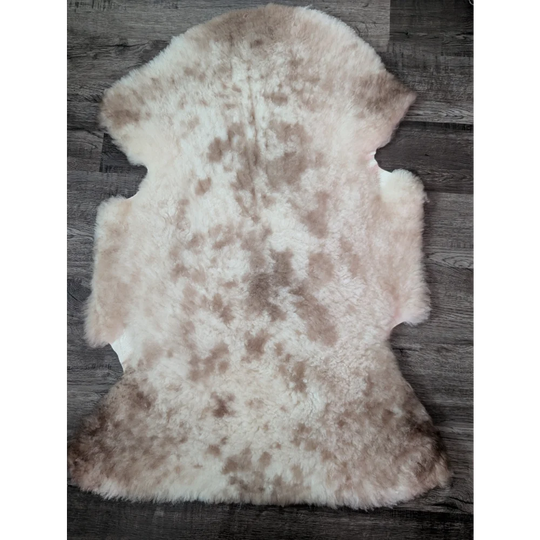 A soft fluffy tibet highland spotted sheepskin rug with natural cream and light brown mottled pattern ideal for decor