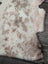 A soft tibet highland spotted sheepskin rug in creamy white and light brown with a natural mottled pattern