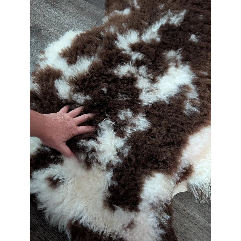 A plush brown and white tibet highland spotted sheepskin rug with soft curly texture measuring 42 by 27 inches
