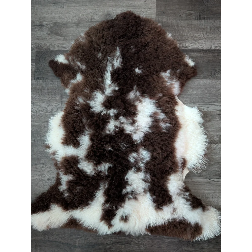 A plush 42x27 inch tibet highland spotted grade a sheepskin rug with natural brown and white patterns and soft texture