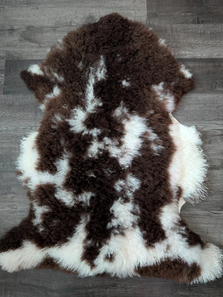 A plush 42x27 inch tibet highland spotted grade a sheepskin rug with natural brown and white patterns and soft texture