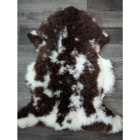 A plush 42x27 inch tibet highland spotted grade a sheepskin rug with natural brown and white patterns and soft texture