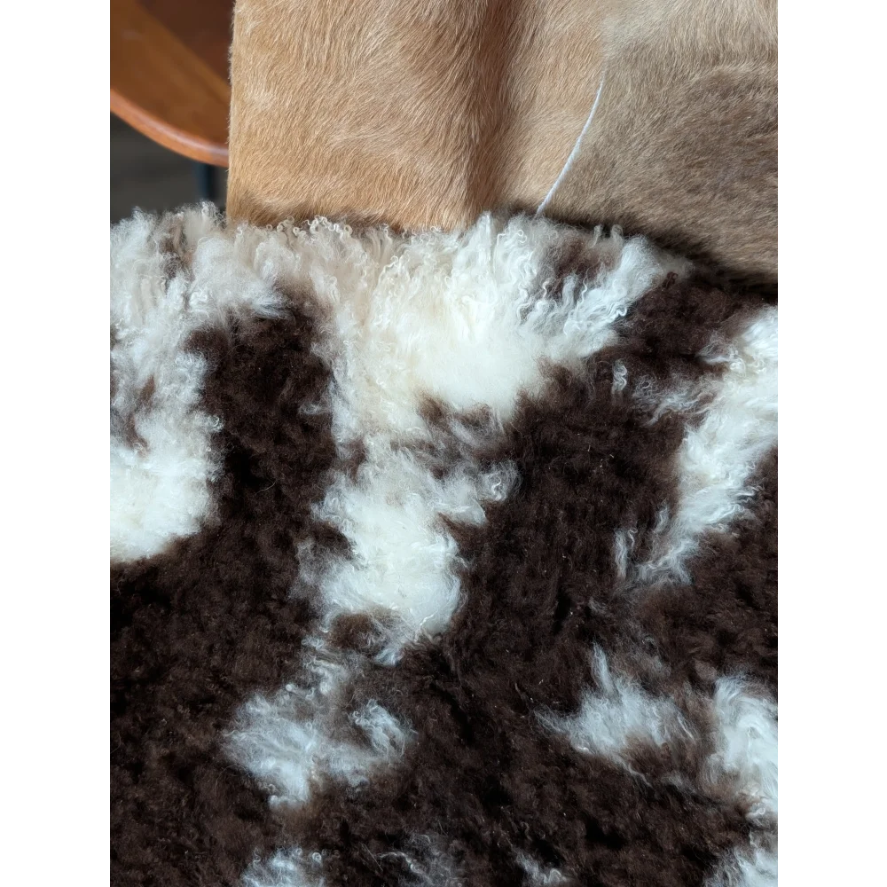 A plush curly brown and white tibet highland spotted sheepskin rug with soft natural texture grade a quality