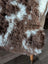 A plush curly brown and white tibet highland spotted sheepskin coat with a natural irregular pattern
