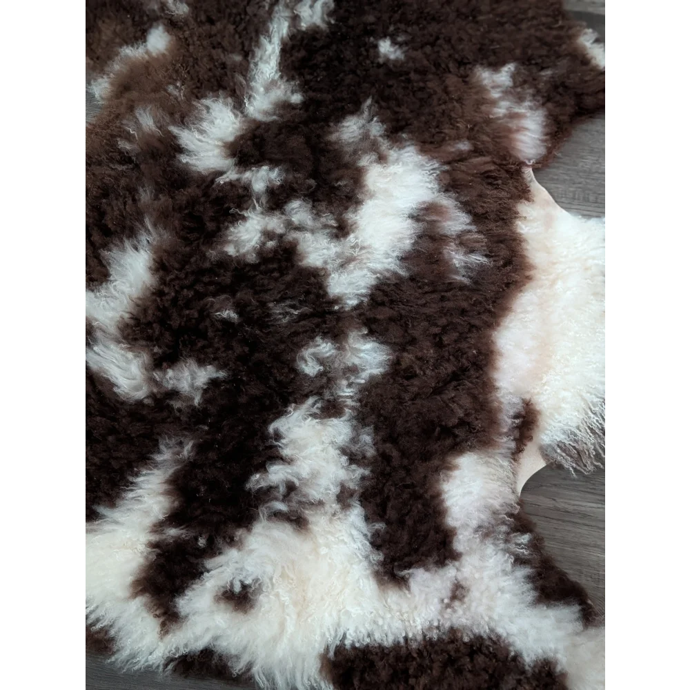 A plush grade a tibet highland spotted sheepskin rug with natural brown and white curly fur measuring 42 x 27 inches