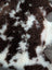 A plush grade a tibet highland spotted sheepskin rug with natural brown and white curly fur measuring 42 x 27 inches