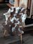 Brown and white tibet highland spotted sheepskin throw draped over a white wooden chair for cozy decor